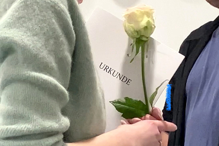 Frau hält Urkunde und Blume