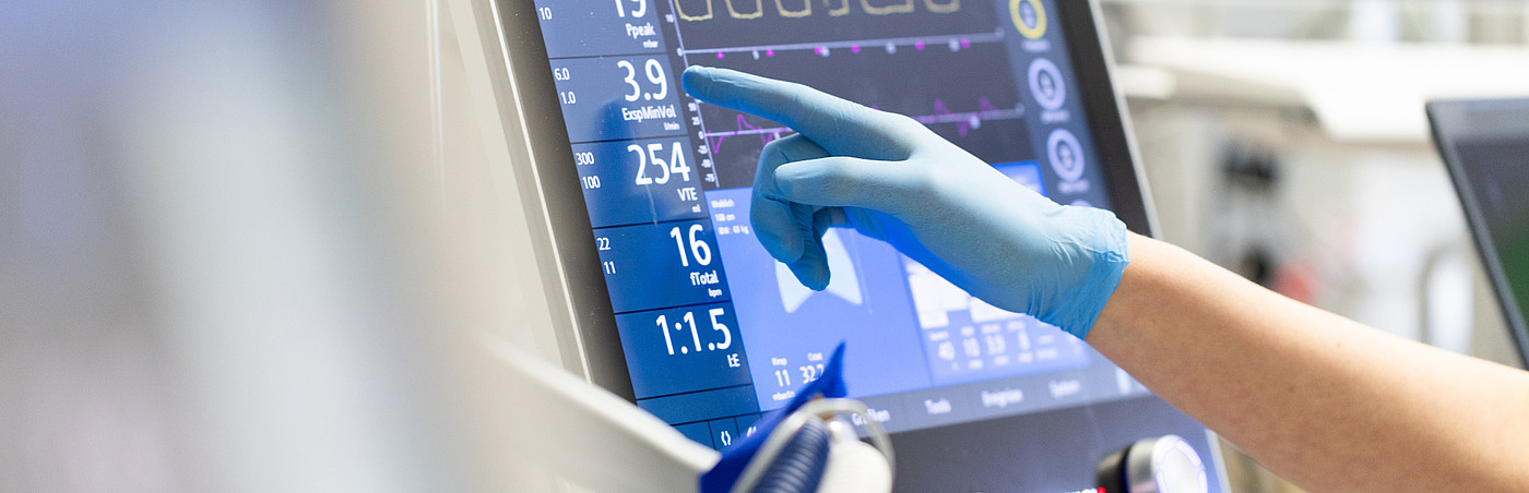 Hand zeigt auf Überwachungsbildschirm auf einer Intensivstation