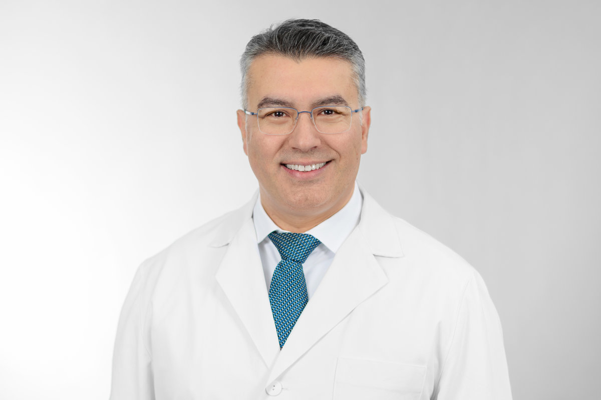 Portrait von Professor Stellos im weißen Arztkittel vor neutral weißem Hintergrund