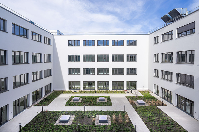 Innenhof der Manfred-Fuchs-Klinik mit begrünten Flächen und umliegenden Klinikgebäuden.