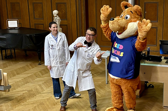 Arzt scherzt mit Maskottchen.