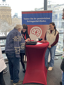 Mann und zwei Frauen am Stand der UMM im Gespräch.