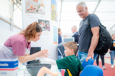 Eine Mitarbeiterin der Kinderchirurgie & Kindernotaufnahme legt einen Gips an den Arm eines jungen Besuchers an.