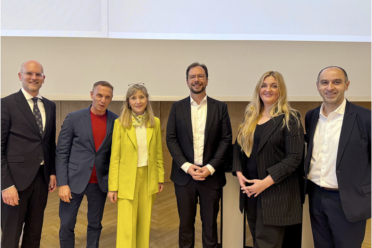 Sechs Personen in Businesskleidung stehen nebeneinander vor einer hellen Wand