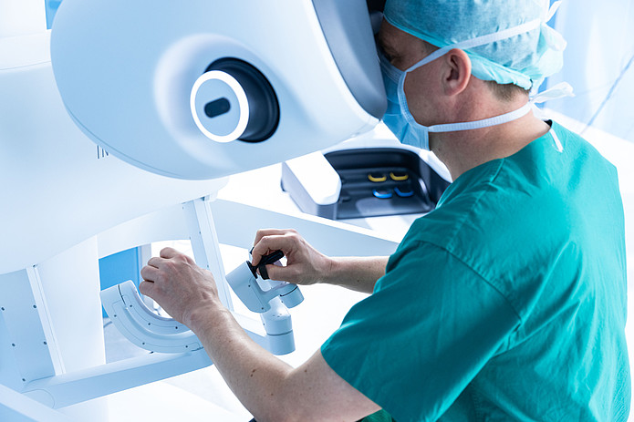 Chirurg bedient die Steuerkonsole eines robotergestützten Operationssystems im OP-Saal.