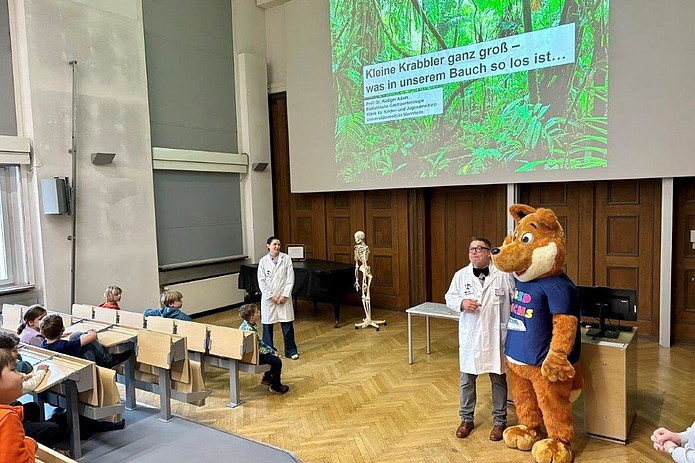 Referenten und Maskottchen in Hörsaal.