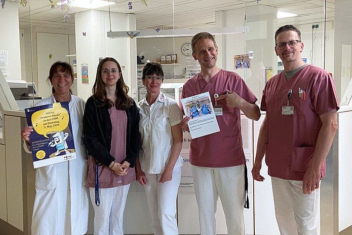 Mehrere Personen stehen gemeinsam in einem Klinikbereich und posieren für ein Gruppenfoto.