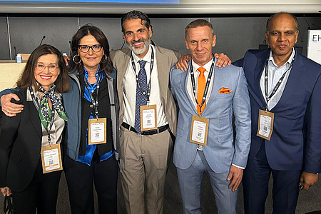 Teilnehmende stehen bei einem internationalen Fachkongress zusammen und posieren für ein Gruppenfoto.