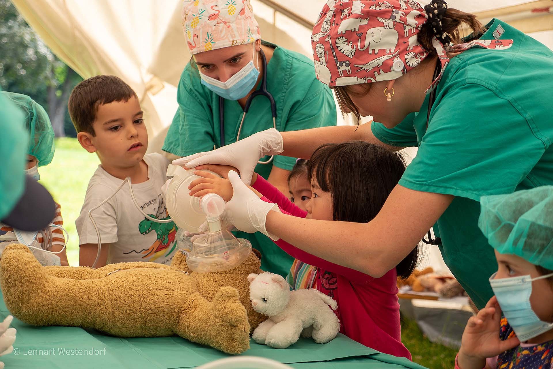 Das Foto zeigt die Teddydocs bei einem Eingriff am OP-Teddy Bruno, mit Unterstützung von mehreren Kindern in OP-Kleidung.