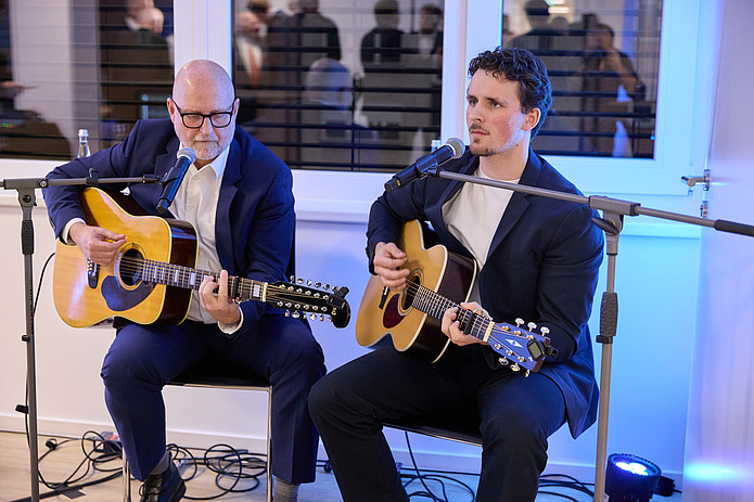 Zwei Gitarristen perfomen im Sitzen