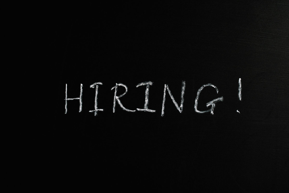 Das Wort 'HIRING!' in weißer Kreideschrift auf schwarzem Hintergrund