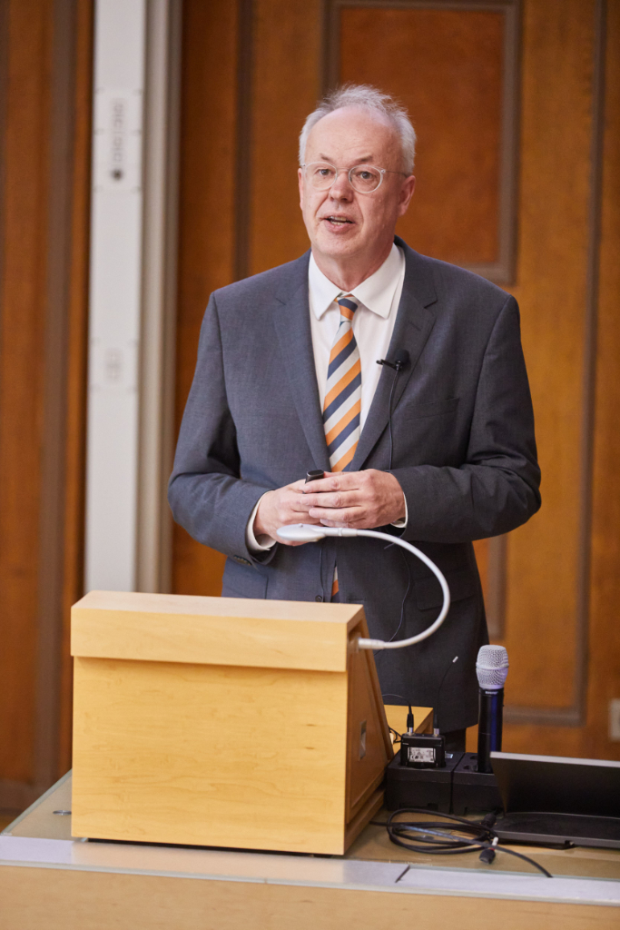 Mann in grauem Anzug spricht in historischem Hörsaal